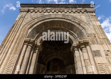 Geschnitzter Steineingangsbogen des Tatev-Klosters mit einer alten Glocke, die im dunklen Tor sichtbar ist, Syunik-Provinz, Tatev, Armenien Stockfoto