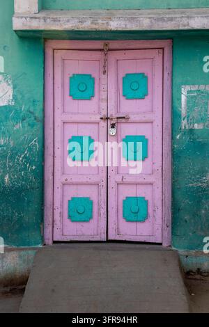 Rosa und türkisfarben gestrichene Holztür mit einem alten Vorhängeschloss verschlossen, Gujarat, Mandvi, Indien Stockfoto