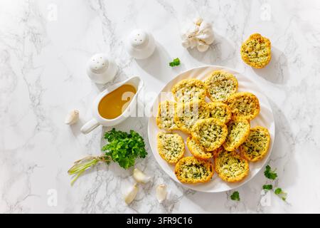 Traditionelle italienische Knoblauch-Crostini, geröstete Brotscheiben mit Kräutern und Butter, serviert auf einem weißen Teller auf Marmortisch mit Olivenöl Stockfoto