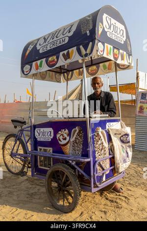 Eisverkäufer steht hinter seinem Shiva-Eis-Tricycle-Wagen auf dem Sand der Maha Kumbh Mela, Uttar Pradesh, Prayagraj, Indien Stockfoto