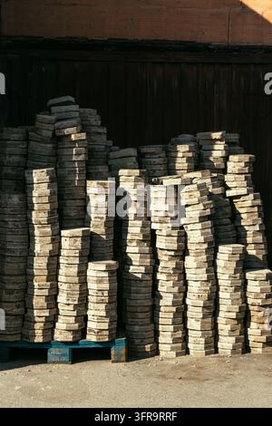 Hoher Stapel von Betonpflastersteinen, gelagert in einem Baustoffhof. Konzept von Pflasterversorgung, Gebäude renovation, Materialien für Landschaftsarchitektur Stockfoto