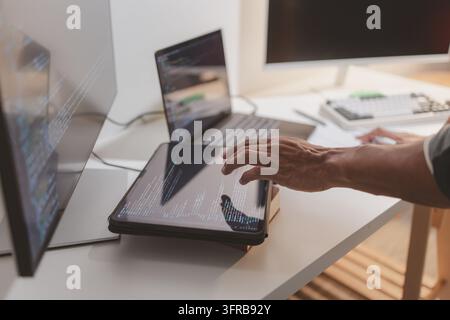 Softwareentwickler codiert auf Laptop und Tablet in einem modernen Arbeitsbereich. Nahaufnahme des Programmierablaufs, Softwareengineering, Debugging von Quellcode, a Stockfoto