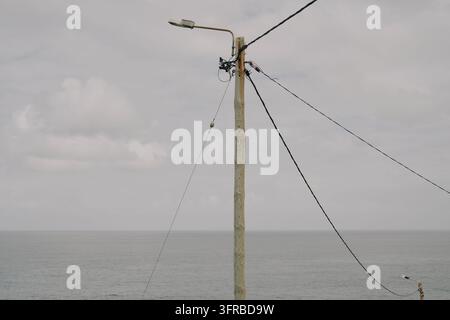 Strommast mit Kabeln, der sich gegen das Meer in Madeira abhebt Stockfoto