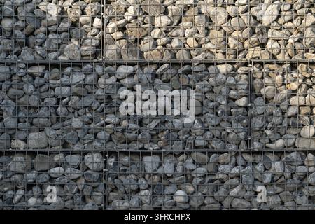 Nahaufnahme einer architektonischen Hintergrundtextur einer stabilen Stützmauer aus Schotter, eingeschlossen in galvanisierten Drahtgitterkäfigen Stockfoto