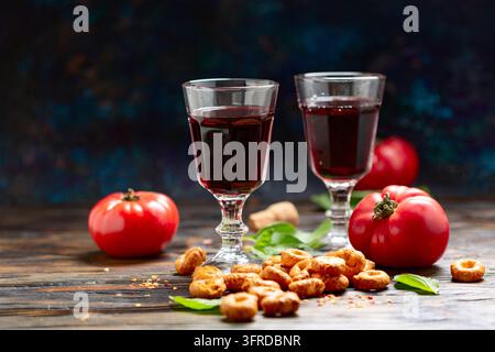 Traditionelle italienische Vorspeise Taralli oder Tortellini mit Tomaten, Basilikum und Gläsern Rotwein auf einem Holztisch. Konzept der traditionellen italienischen Küche Stockfoto