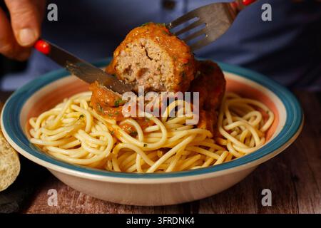 Nahaufnahme eines Mannes, der einen Teller Fleischbällchen mit Spaghetti isst Stockfoto