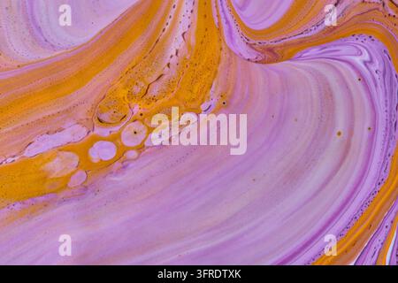 Abstrakte flüssige Kunsttextur mit wirbelnden lila, rosa und lebendigen gelben Acrylfarbenblasen Stockfoto