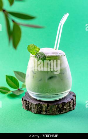 Kalter grüner Matcha-Tee gemischt mit Eiswürfeln und Milch auf einem Holzständer. Kopierraum. Konzept von eisgekühlten Sommergetränken Stockfoto
