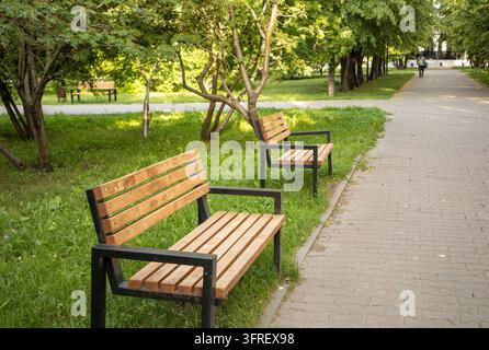 Zwei neue Holzbänke stehen entlang der Gasse im städtischen Sommerpark Stockfoto