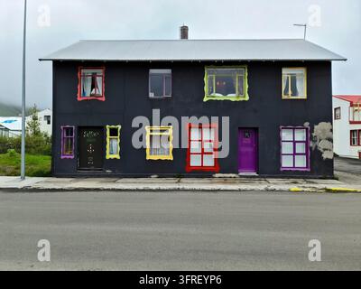 Island, Akureyri 22. Juni 2024, Schwarze Fassade eines Gästehauses mit bunten Fensterrahmen und violetter Tür in Akureyri Stockfoto