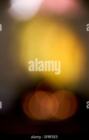 Weicher und verträumter abstrakter Hintergrund mit verschwommenen goldenen, gelben und orangen Bokeh-Lichtern vor einem dunklen, warmtönigen Hintergrund. Dieser lebendige und sp Stockfoto