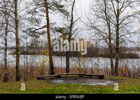 Pittoreske horizontale Landschaft eines leeren Picknickplatzes an ruhigem Wasser unter bewölktem Himmel in Nordeuropa. Stockfoto