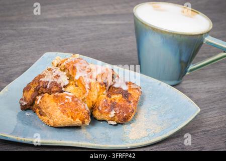 Frisch gebackenes polnisches Gebäck mit Mohnfüllung auf rustikalem hellblauen Teller und einer Tasse Kaffee. Traditionelle Martin's Croissants aus der polnischen Stadt Posen Stockfoto