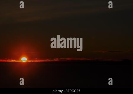 Feurige orange Sonne, die über dem Meer in Punta Arenas, Chile, untergeht Stockfoto