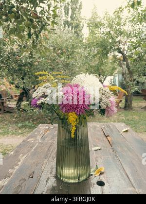 Frisches Herbstbouquet aus Astern und Wildblumen in einer Glasvase im Freien Stockfoto