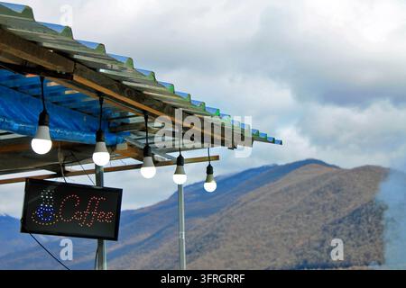 Kaffeeschild auf dem Dach eines lokalen Marktstandes mit Glühbirnen am Straßenrand in der Bergregion von Georgia Stockfoto
