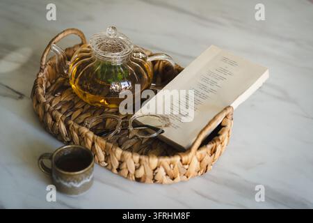 Heißer Tee, Buch und gemütlicher Lesemoment in einem Weidenkorb Stockfoto