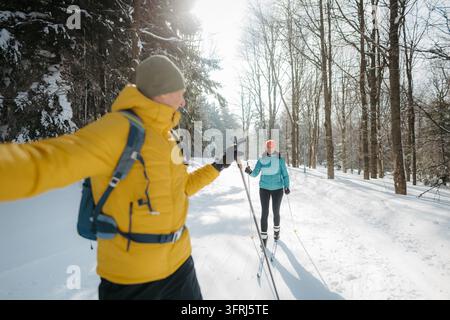 Aktives reifes Paar geht gemeinsam Langlauf im verschneiten Wald. Stockfoto