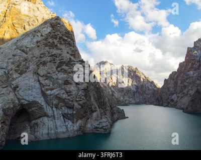 Luftbild von türkisblauem Seewasser, das von steilen Felswänden und schroffen Berghängen eingerahmt ist Stockfoto