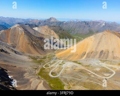 Panoramischer Luftbildblick auf eine Serpentinenstraße, die sich durch ein Hochgebirgspass-Tal windet Stockfoto