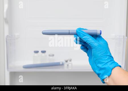 Diabetesmanagement und Insulintherapie, Person in medizinischen Handschuhen nimmt Medikationsstift aus dem Kühlschrank für die tägliche Behandlung und Gesundheitsvorsorge Stockfoto