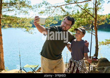 Vater und Junge machen Selfie mit Smartphone beim Angeln Stockfoto
