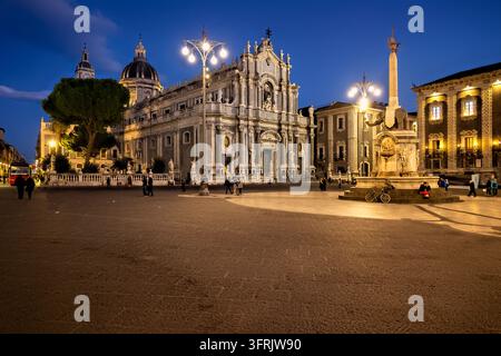 Piazza del Duomo in Catania, Sizilien, Italien, mit der Sant'Agata-Kathedrale und dem aus Lavagestein gebauten Fontana dell'Elefante, der bei Einbruch der Dunkelheit von Straßenlaternen beleuchtet wird. Stockfoto