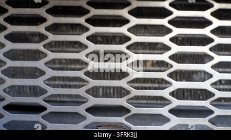 Regenschlieren auf Metallabflussgitter, Wasser durch sechseckige Öffnungen. Stockfoto