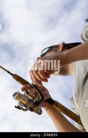 Niedrigwinklige Ansicht eines Mannes, der eine Angelrute und eine Angelrolle hält Stockfoto