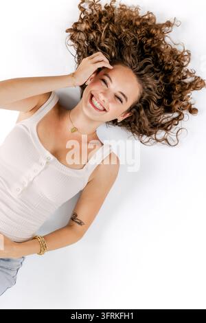Glückliche junge Frau mit voluminösem lockigem Haar Stockfoto