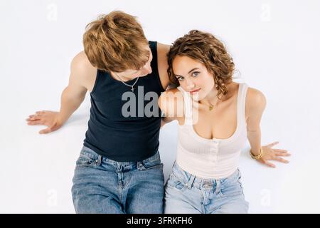 Hochwinkelaufnahme eines jungen Paares, das auf weißem Studiohintergrund sitzt Stockfoto