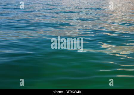 Klarer türkisfarbener Wasseroberfläche der Adria in Kotor, Montenegro mit sanften Wellen und Sonnenlichtreflexionen. Stockfoto
