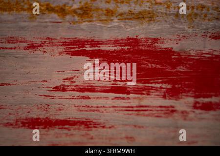 Nahaufnahme einer verwitterten Holzoberfläche, bedeckt mit strukturierten Strichen roter und grauer Farbe sowie rostigen Flecken, ideal für modernes Design Stockfoto