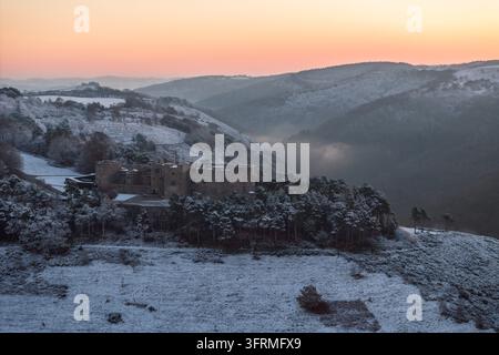 Sonnenaufgang über dem schneebedeckten Castle Drogo an einem kalten Wintermorgen, Dartmoor-Nationalpark, Devon, England. Winter (Dezember) 2023. Stockfoto