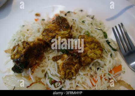 Lammhirnbraten serviert mit Gemüse-Biryani-Reis auf einem weißen Teller, Nahaufnahme eines indischen scharfen Bheja-Fry oder Ziegenhirn-Masaladishs Stockfoto