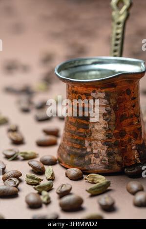 Traditionelle Kaffeekanne, geröstete Kaffeebohnen und Kardamomkapseln auf braunem Hintergrund, selektive Fokussierung Stockfoto