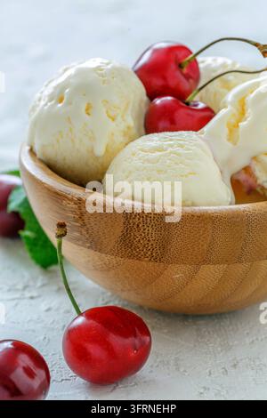 Schale mit Eiscreme und süßen Kirschen auf einem weißen Betonhintergrund Stockfoto