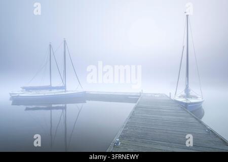 Yachten am Pier im dichten Nebel am See Stockfoto