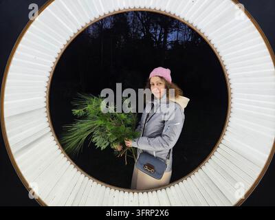 Frau hält einen Bündel grüner Blätter in der Hand. Sie steht vor einer weißen Kreislampenstudio im Park Stockfoto