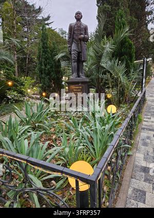 Sotschi - 31. Dez. 2023: Statue eines Wissenschaftlers Lomonossow befindet sich in einem Garten. Die Statue – der erste bedeutende russische Naturwissenschaftler – ist von Pflanzen umgeben und hat eine Plakette in Sotschi. Stockfoto