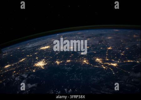 Stadtlichter leuchten über der gekrümmten Oberfläche der Erde bei Nacht, wie aus dem Orbit gesehen, mit einem dünnen grünen Band von Luftleuchten entlang des Horizonts und Sternen, die verstreut sind Stockfoto