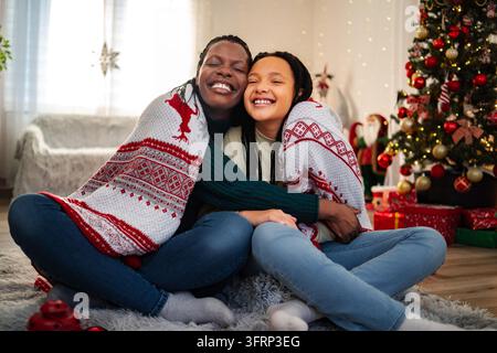 Afroamerikanische Mutter und Tochter teilen eine herzliche Weihnachtumarmung Stockfoto