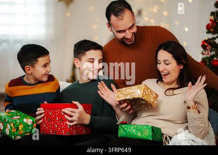 Familie öffnet Weihnachtsgeschenke und feiert die Feiertagssaison zu Hause Stockfoto