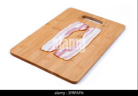 Zwei Scheiben Speck auf einem Holzbrett, Seitenansicht, weißer Hintergrund Stockfoto
