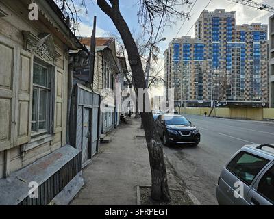 Straße mit einem Baum in der Mitte und einem parkenden Auto an der Seite. Es gibt mehrere alte und neue Häuser an der Straße in Samara Stockfoto