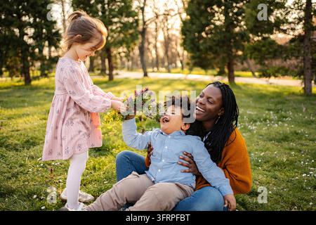 Mutter und Kinder, die im Park mit Blumen spielen Stockfoto