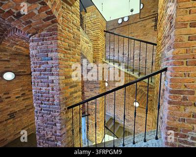 Die Treppe ist aus Ziegel und Metall gefertigt, mit einem schwarzen Geländer. Es ist eine Wendeltreppe, die ein einzigartiges und interessantes Design hat. Die Treppe befindet sich in einem Gebäude mit einer Ziegelfassade Stockfoto