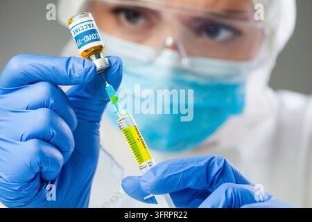COVID-19-Impfstoff, Coronavirus-Impfkonzept, Arzt Hände in blauen Handschuhen halten Medizin Impfstoffflasche und Spritze, Zeichnung Booster SARS-CoV-2 Stockfoto