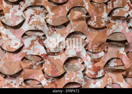 Eine Nahaufnahme von Wüstendigital-Tarnnetzen. Der Stoff weist ein welliges, gestanztes Netzmuster in den Farben Beige, Braun und Sand auf und dient als Tac Stockfoto