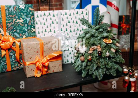 Weihnachtsgeschenke und geschmückter Miniaturtannenbaum mit festlichen Ornamenten Stockfoto